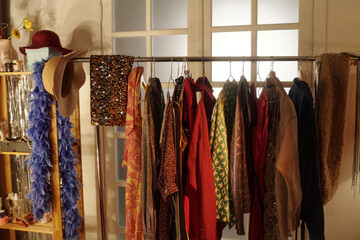 Garment rack full of colorful costumes featuring various fabrics and textures in a warmly lit room...