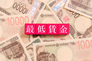 一万円札とブロックの上に書かれた最低賃金　経済