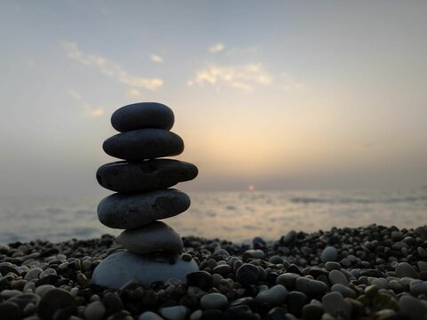 Serene beach scene with stacked pebbles at sunset.