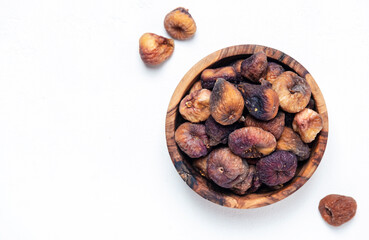 Organic sun dried figs in wooden bowl on white background, top view