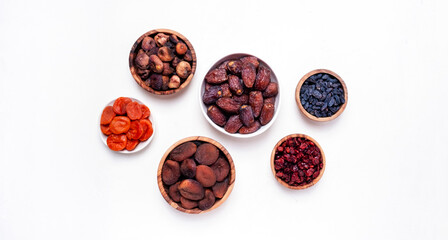 Organic sun dried fruits in bowls on white background. Healthy wholesome snacks instead of sugar and candy, source of vitamins and microelements. Top view