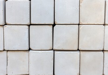 A neatly stacked grid of speckled white square blocks, forms a robust and textured building material, suggesting a foundation or construction element