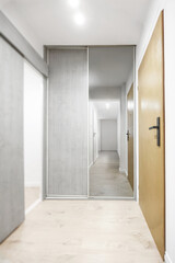 Narrow hallway in a small apartment in a building, with walls being freshly painted, highlighting a cozy and refreshed interior