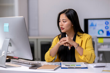 A woman is sitting at a desk with a computer monitor in front of her