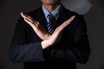 手で罰を作るビジネスマン(暗め)