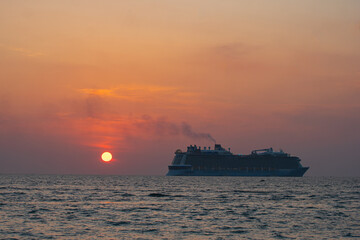 The sun setting on a luxury cruise ship paints the sky with hues of orange and pink, creating a breathtaking view. scene the day gracefully transitions into night at Patong beach Phuket.
