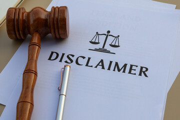 A professional office arrangement showcasing a disclaimer document with a judge’s hammer and pen, signifying legal policies and liability regulations.