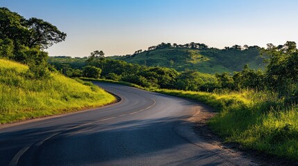 Fototapeta premium A winding road through lush green hills under a clear blue sky.