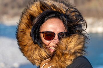 portrait of a beautiful middle-aged woman in winter clothes and sunglasses in front of a landscape...
