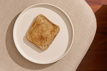 Toasted slice of bread on modern white plate and bright background with beautiful morning sunlight....