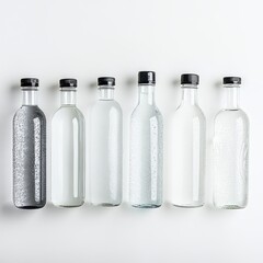 Five glass bottles with black caps, filled with clear liquid, arranged in a row on a white background.