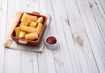 Traditional brazilian fried manioc in a plate over wooden table with copy space