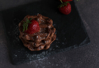 dessert pastry chocolate waffles with strawberries on a dark background