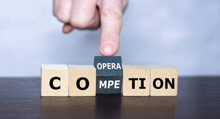 Hand turns cube and changes the word competition to cooperation. 