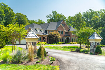 Landscape with large country house. Driveway for car. Green trees in the garden.
