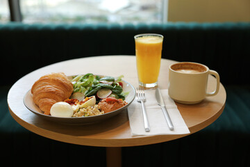 Tasty breakfast. Freshly baked croissant and salad served on wooden table in cafe