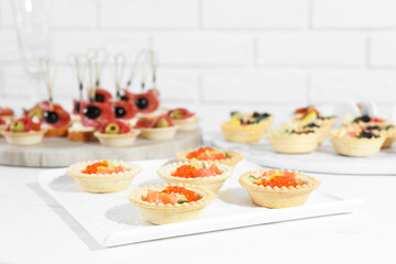Many different tasty canapes on white wooden table, closeup