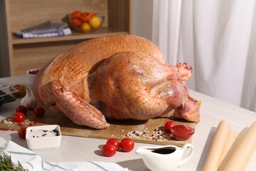 Whole raw turkey with marinade and ingredients on white wooden table