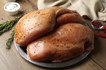 Raw marinated turkey breasts on wooden table, closeup