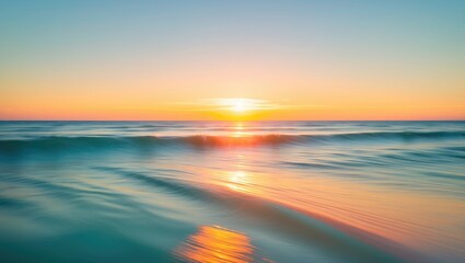 Obraz premium Sunset over calm ocean waves with vibrant colors reflecting in the water against a clear sky by the horizon.