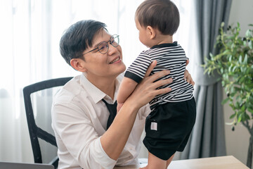 Father shares a joyful moment with his baby at home during working hours while embracing family life