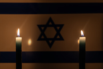 Mourning in country Israel. A burning candle on the background of Israeli flag. Victims of...