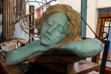 Sculpture of a woman resting her head on her arms with eyes closed.