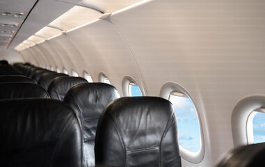 Airplane cabin interior,Empty comfortable row seats in economy class with portholes,Aerial view through airplane window,Inside Passenger plane looking out at cloud sky,Concept for transport Travel