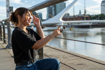 Young woman placing love lock on puerto madero waterfront in buenos aires