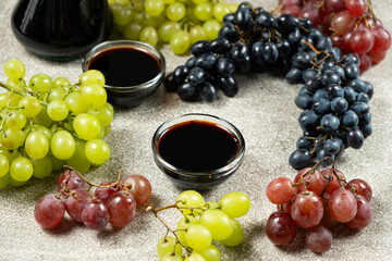 Balsamic vinegar poured into a glass sauce dish among the grapes