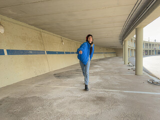 A woman is running in a parking lot. The parking lot is empty and the woman is the only person in the scene
