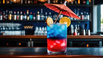 Colorful layered drink with ice, lemon slices, and decorative umbrella on a bar counter, with blurred bottles in the background.