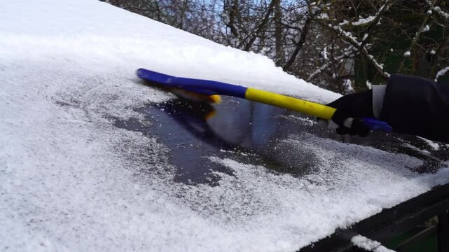 Cleaning ice from solar panels with a brush