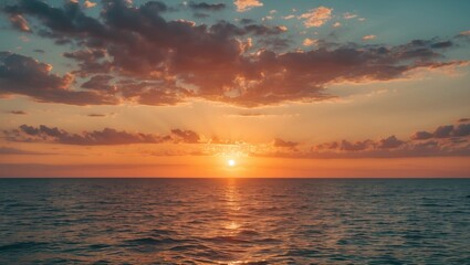 Obraz premium Sunset over calm ocean water with cloudy sky reflecting warm colors and light rays in the horizon during twilight hours