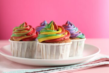 Delicious cupcakes with colorful cream on pink table, closeup