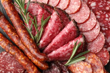 Different smoked sausages slices and rosemary on table, closeup