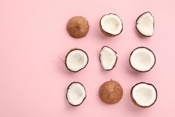 Pieces of cracked coconuts on pink background, flat lay. Space for text