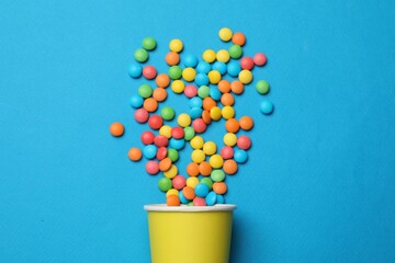 Colorful sugar coated dragee candies on blue background, top view