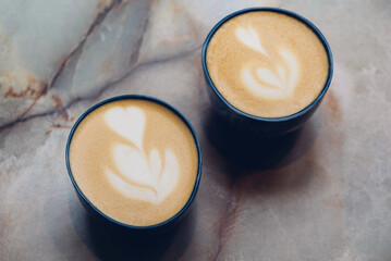 Two cups of fresh delicious cappuccino coffee with beautiful latte art on marble background. ...