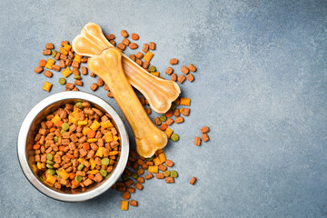 Pet bowl with dry food on a gray textured background. Studio photo.