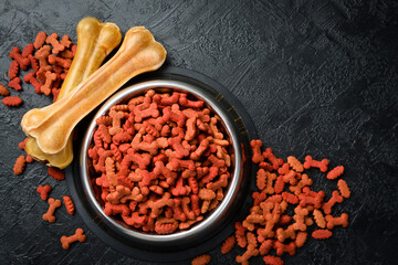 Dog food in a bowl. Organic grain food for dog on a black stone background. Top view.