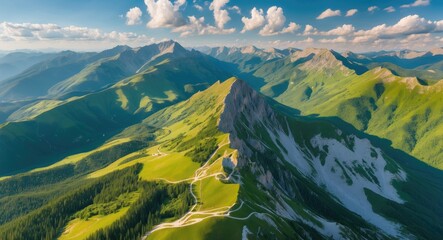Aerial view of lush green mountains with rugged peaks under a bright blue sky dotted with fluffy clouds and winding paths through the landscape