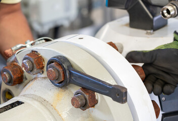 Removing rusty bolts from a pipeline flange using a wrench during maintenance.