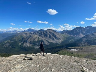 Lone hiker stands atop a rugged mountain ridge in Jasper National Park, gazing at the peaks