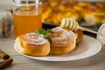 Pastries. Sweet buns with cottage cheese filling and honey in a plate on a wooden table