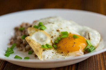 Homemade breakfast with scrambled eggs, boiled buckwheat and greens
