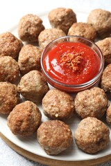 Delicious meatballs with ketchup and spices on light table, closeup