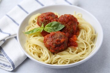 Delicious pasta with meatballs in bowl on light table, closeup