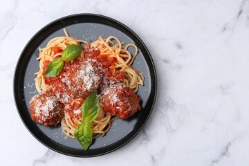 Delicious pasta with meatballs, basil and cheese on white marble table, top view. Space for text