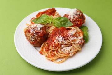 Delicious pasta with meatballs, cheese and basil on green table, closeup